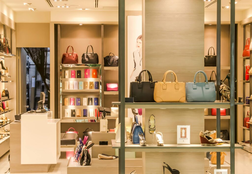 Interior de una tienda de moda con bolsos, zapatos y accesorios organizados en estanterías que vende mediante performance max 